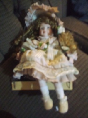 A porcelain doll on a swing.
