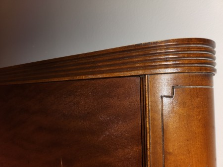 A close up of the carved top of the bed frame.