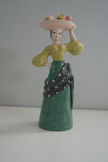 A figurine of a woman carrying fruit on her head.