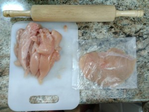 Chicken breasts being pounded flat in a recycled cake mix bag.