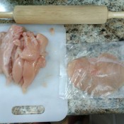 Chicken breasts being pounded flat in a recycled cake mix bag.
