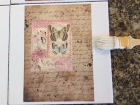 Adding modpodge to the paper on the tile.