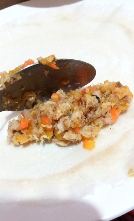 Adding a portion of the mix to the Shanghai wrapper.