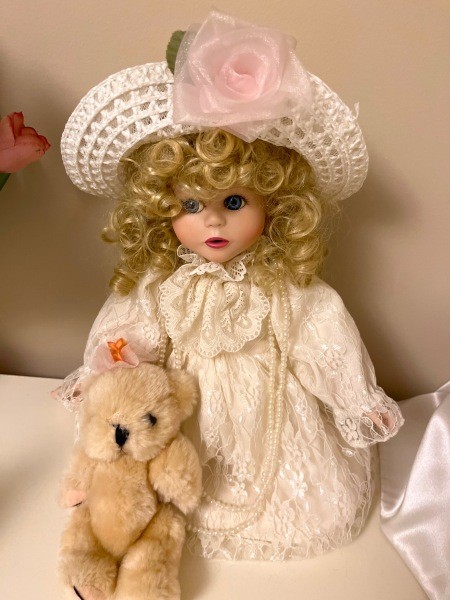 A porcelain doll wearing a white outfit.