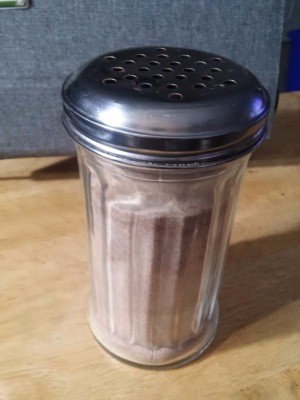 A shaker with cinnamon and sugar.