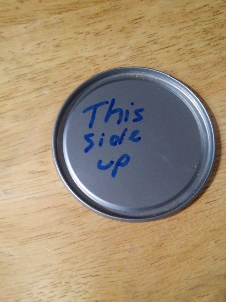 A juice lid with "This Side Up" written on it.