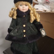 A porcelain doll with a winter coat and hat.