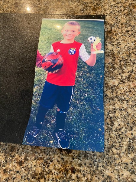 A full body photograph of a boy in his soccer uniform.