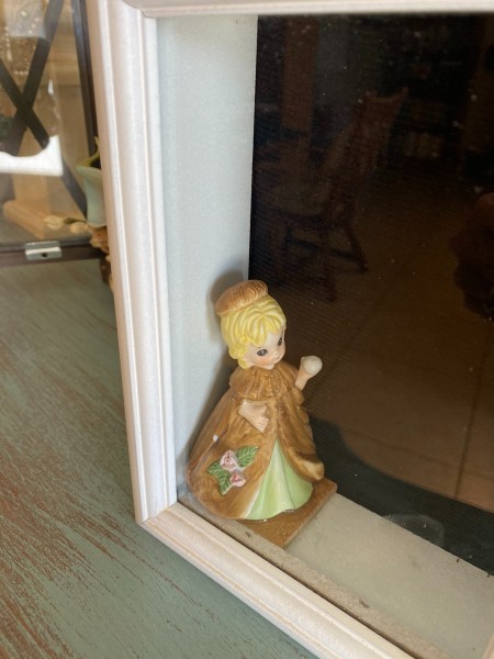 A small figurine in the shadow box frame.