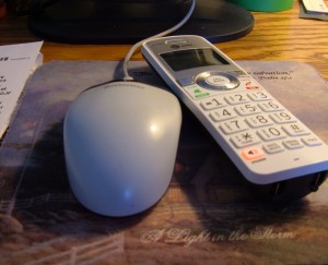 A phone next to a computer mouse.