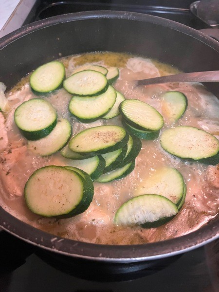 Adding zucchini to the pan.