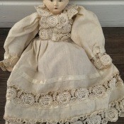 An antique half doll in a lace dress.