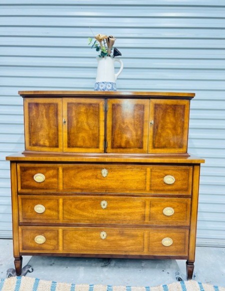 A wooden dresser with cabinets above the drawers.