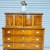 A wooden dresser with cabinets above the drawers.