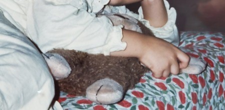 A stuffed monkey in a child's arms.