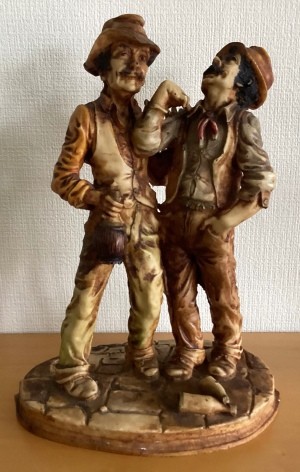 A figurine of two men wearing hats and vests.